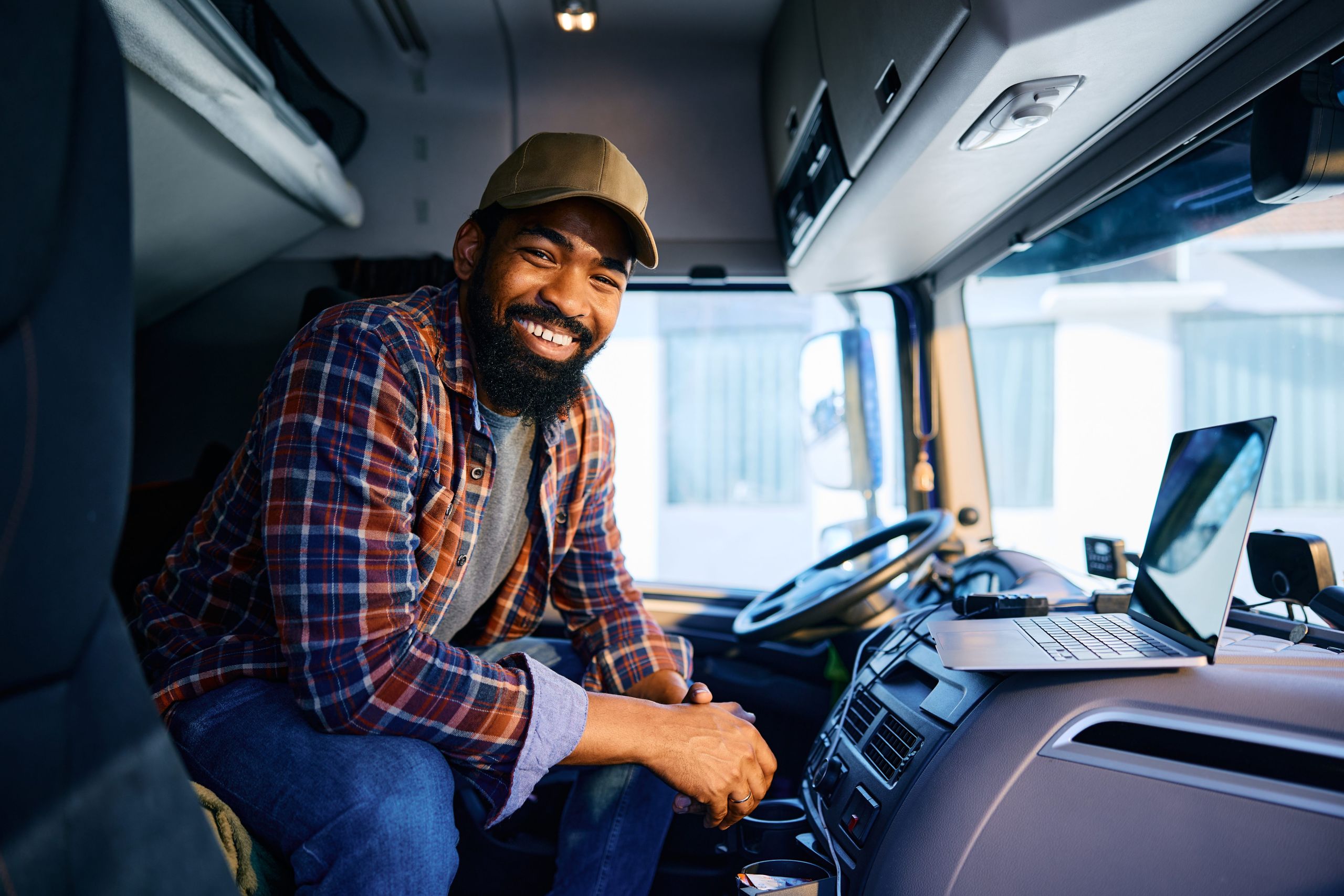 Truck Driver Finding Loads with Loadlink Smiling truck driver inside a cab using a laptop to find freight loads with Loadlink.